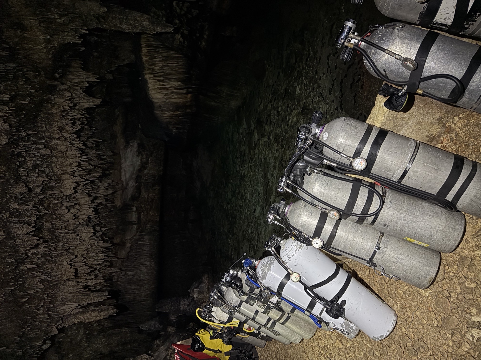 Staged cylinders lined up inside a Mallorca sea cave before a dive